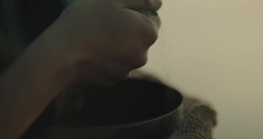 A person is outdoors with a bowl of sand