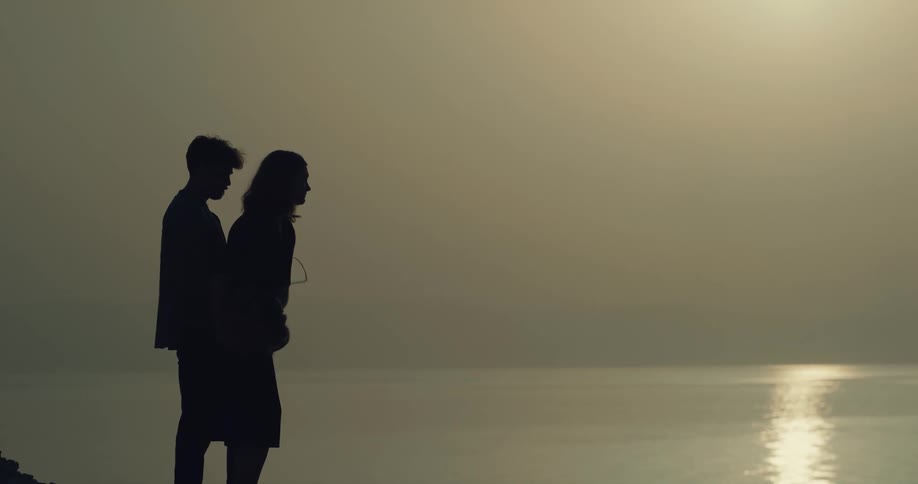 A man and woman toss ashes from an urn into the ocean