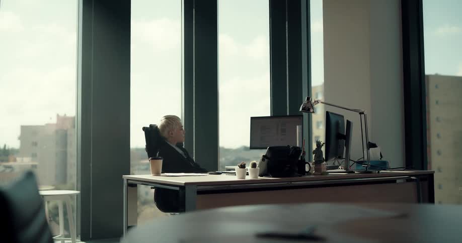Young short haired blonde woman sitting on a desk working at the office