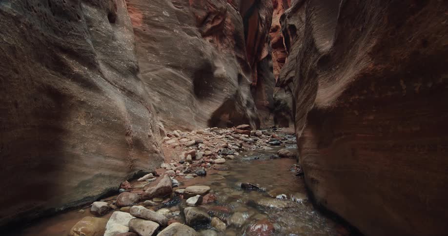 Water in a creek is flowing through large and smooth rocks in a cave