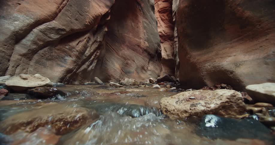 Water is flowing in a creek through rocks in a canyon