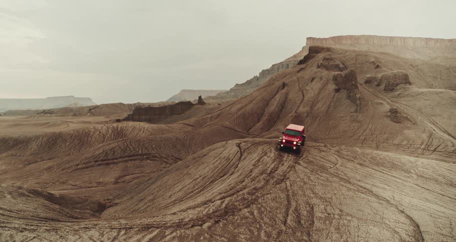 A car is driving off road through a desert area