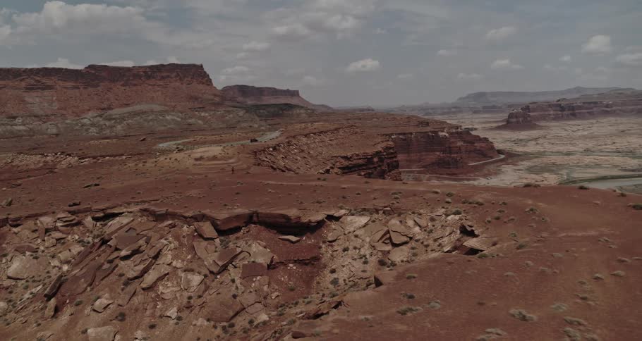 Aerial view of the badlands as someone walks on top of a mountain canyon with a river below