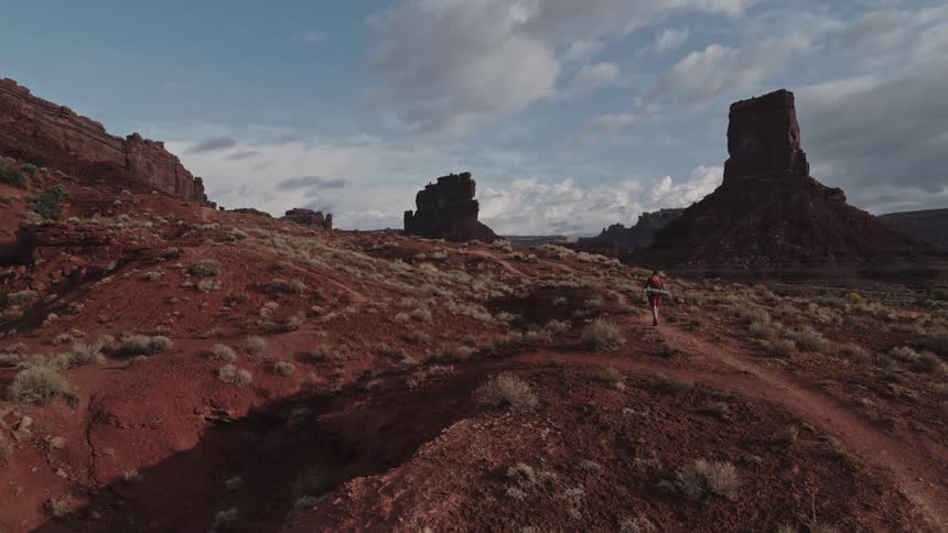 A man hikes on a trail through a canyon