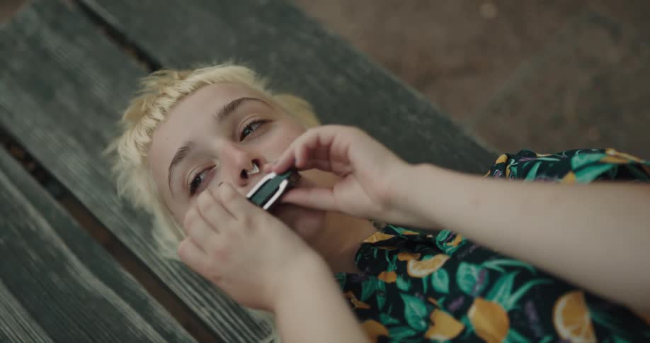 A woman is laying down on a bench outdoors