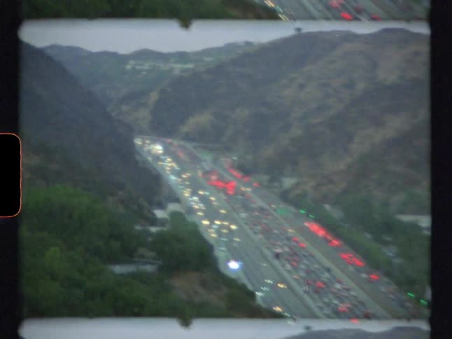 Cars are traveling on a busy mountain freeway after sunset