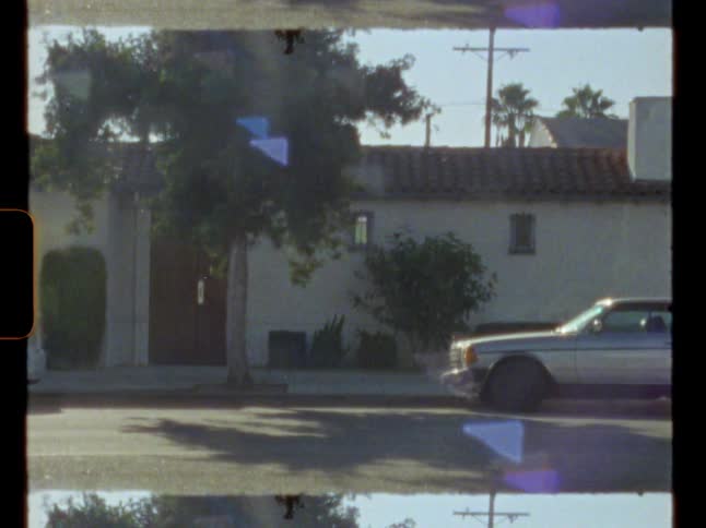 Vintage film footage of a car parked in front of a house