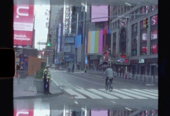 Cars and people are traveling down a commercial city street between tall buildings