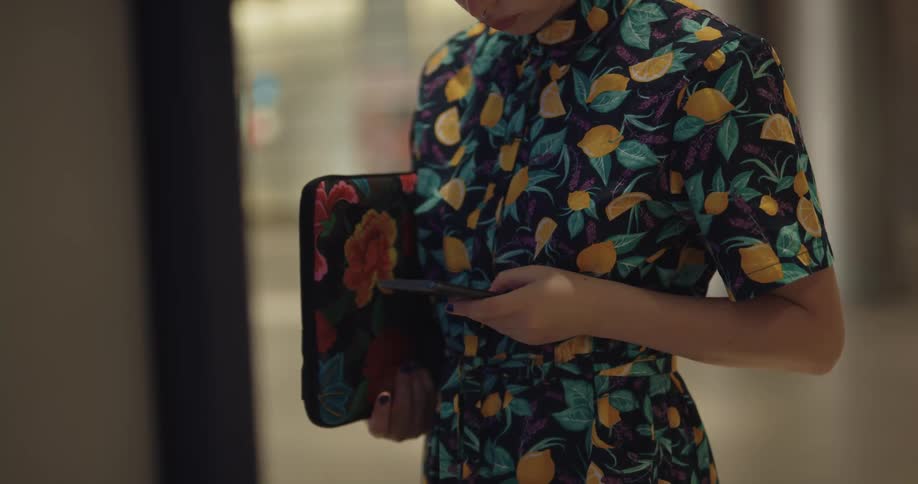 A woman looks at a kiosk then back down at her phone