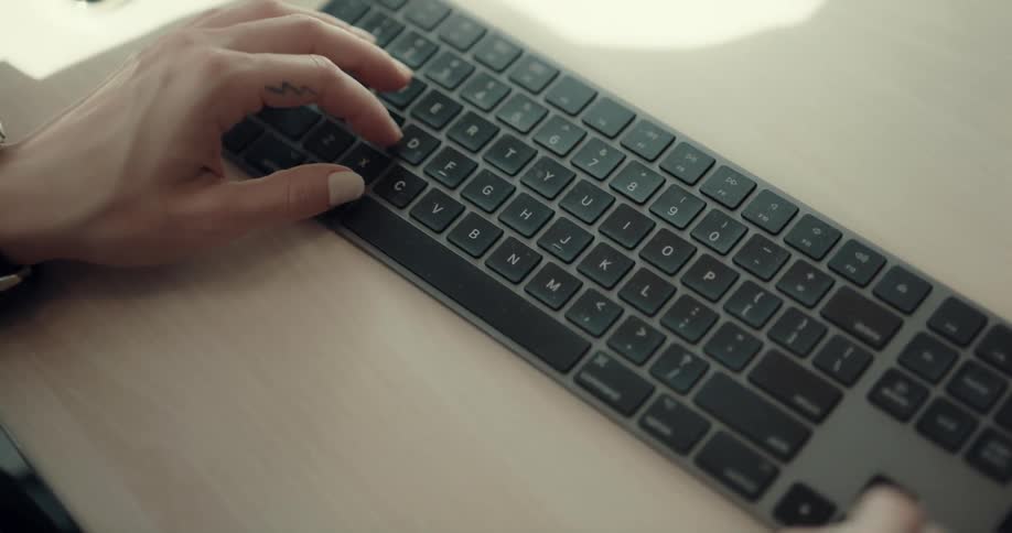 A man is typing on a keyboard at his desk