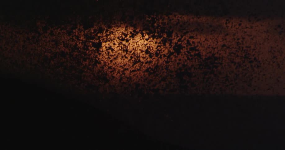 A slow motion sea wave bursts into the air in front of an ocean sunset