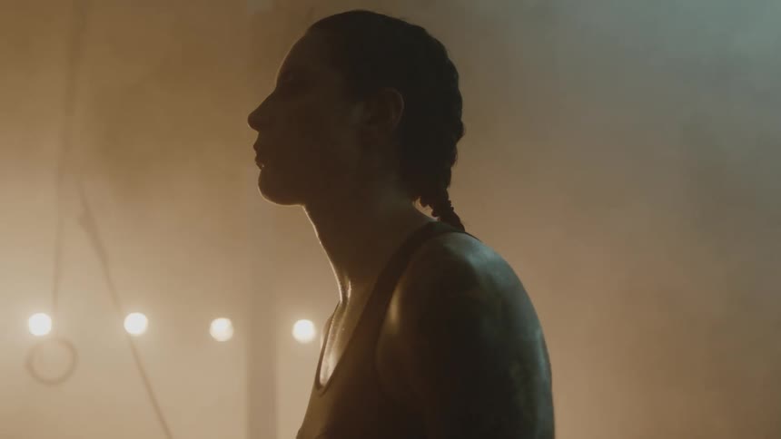 Female boxer with braids sports bra and fight trunks stands in boxing ring