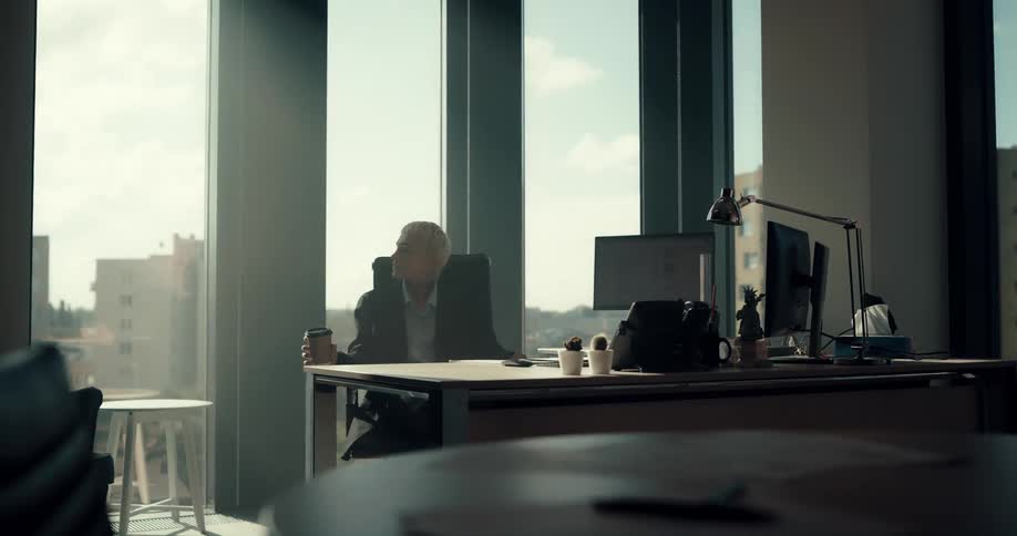 A woman sips coffee and spins in her office chair in a high rise building