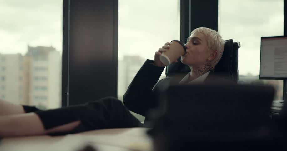 A female employee is drinking a cup of coffee in her office
