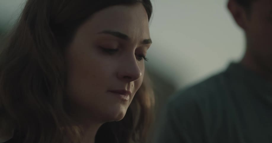 Grieving woman standing behind a man outdoors at evening