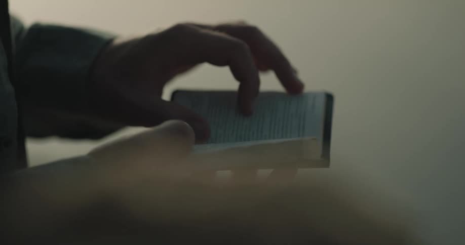 A person is reading pages on a book outdoors