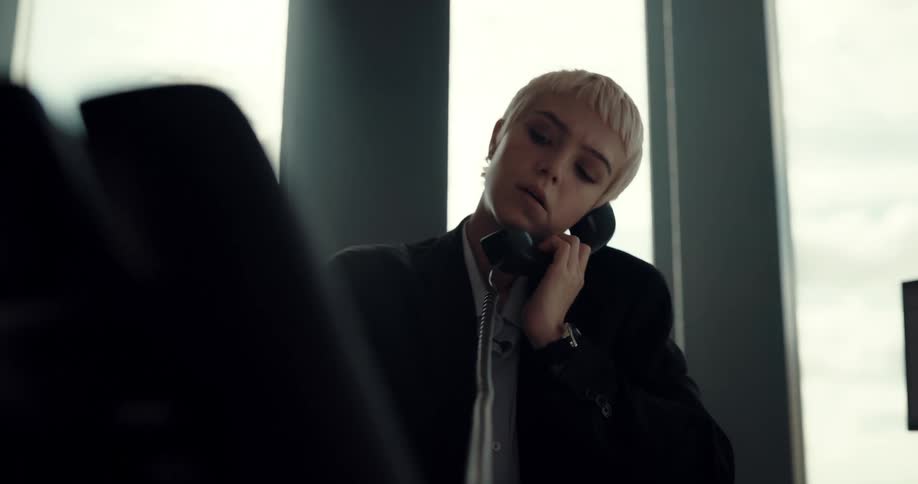 Business woman sits in office talking on the phone