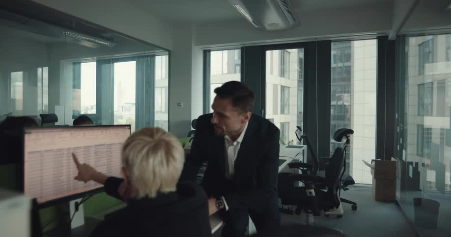 A female employee flags down her boss as he walks by to discuss a spreadsheet