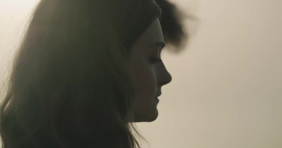 A woman holds a container and stands outside next to a man with a tear running down her face