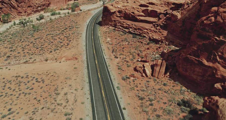 A car is driving on a road in a mountainous area
