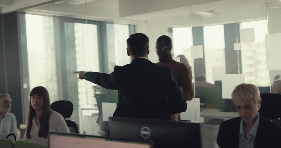 A man waves around a stack of papers while yelling at the workers of an office before throwing the papers and storming away