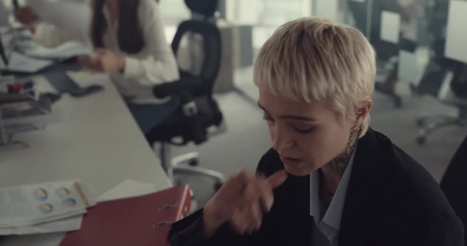 Stressed blonde short haired woman sitting at a desk in the office worried about her work