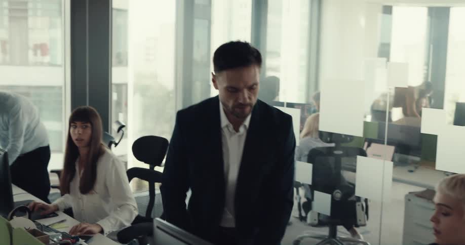 A male walks over to a female office employee and throws papers on her desk