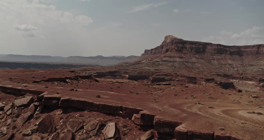 River winds through canyon in badlands toward mist covered mountains on the horizon
