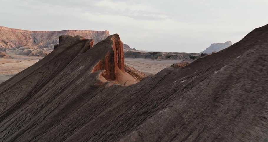 Peaks on a mountain ridge and a mesa in the distance under a cloudy sky