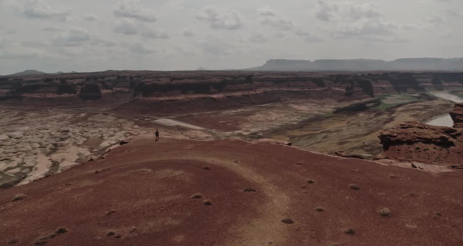 A man stands on the top of a mountain overlooking a river