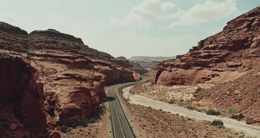 Aerial view of an automobile traveling on a mountain canyon road under a cloudy sky