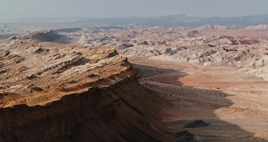 Aerial view of rough mountainous terrain and mountains on the horizon under a hazy sky