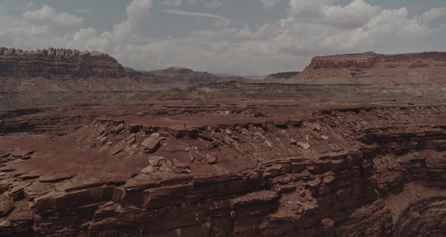 A man stands on the edge of a cliff in a canyon