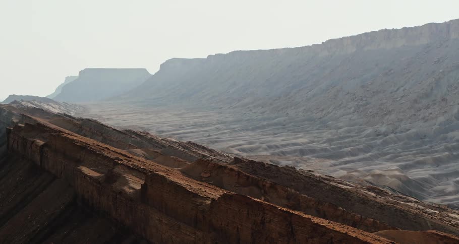 A mountain valley and mesa under a hazy sky