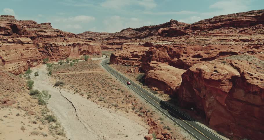 A car is driving on a road through a desert area
