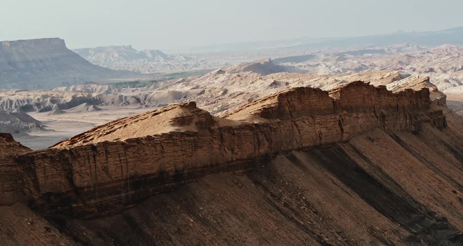 Aerial view of mesa and rock formations in the desert badlands under a hazy sky