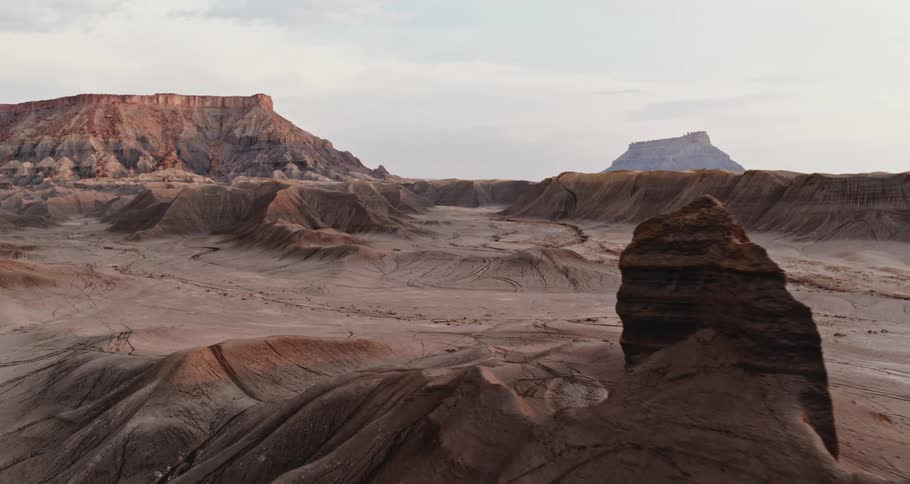 Rock formations and mesa in the desert badlands under a hazy sky