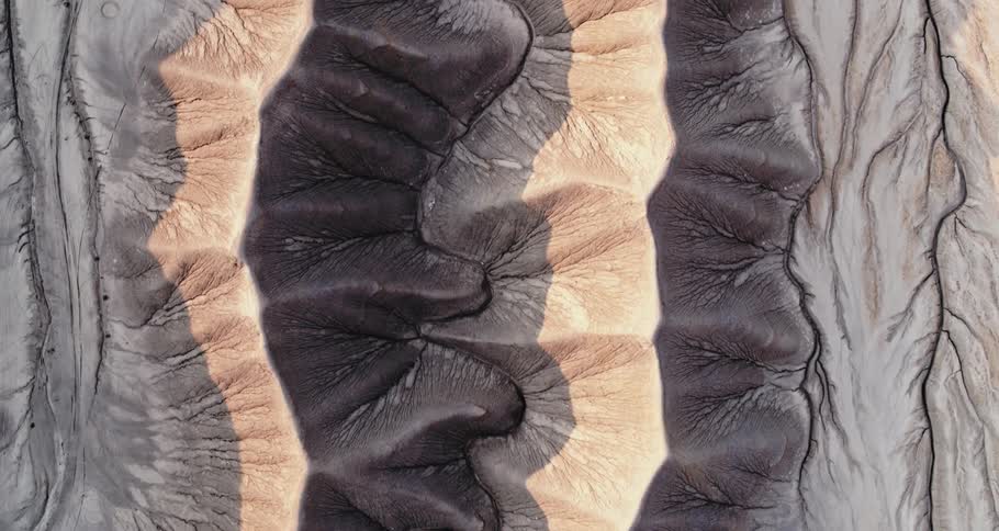 Uneven lined textured surface is colored in bands of shades of gray and pink