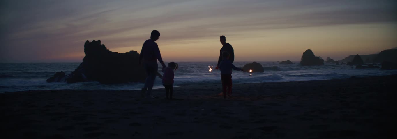 A family plays with sparklers on the beach