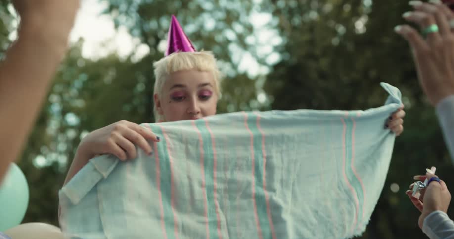 Women are celebrating in a park as one opens gifts