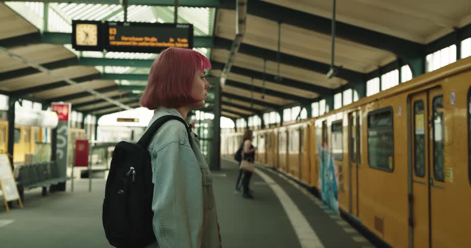 A woman looks at her cell phone while waiting for a subway train