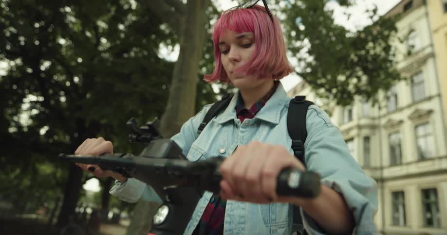A young woman checks her smartphone before putting it away and riding a bicycle out of frame