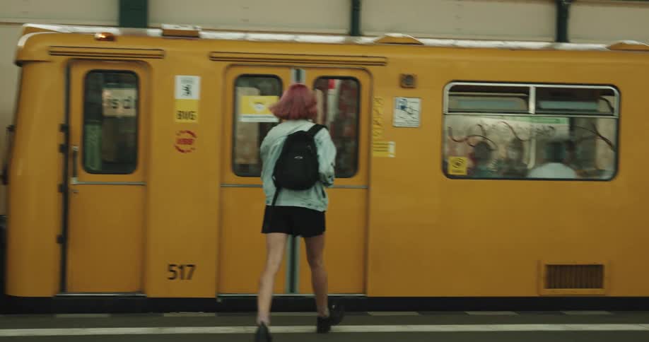 A woman runs up the stairs and gets on the train