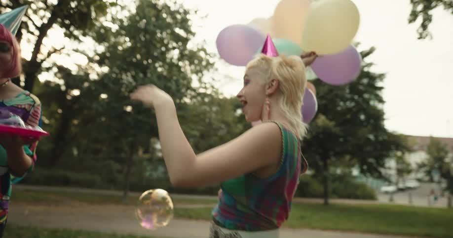 A group of young women play with bubbles at a park