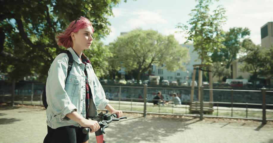 A woman rides an electric scooter down a park path