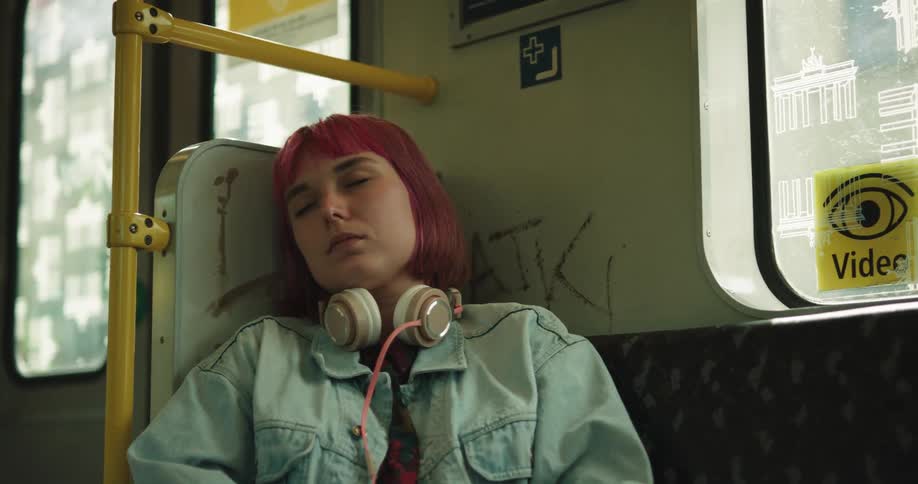 A red haired woman has her eyes closed as she is travelling in a bus