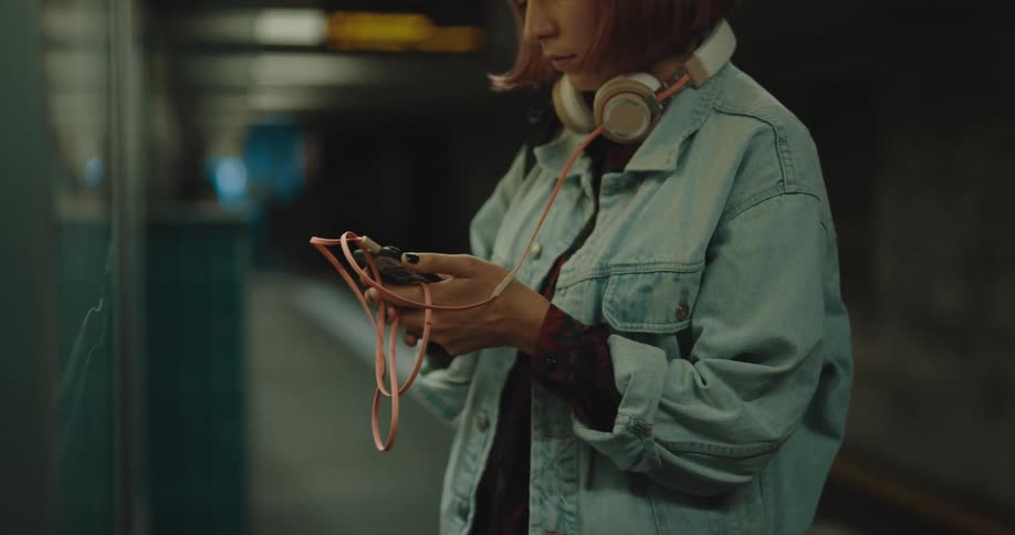 A woman checks her phone in the train station