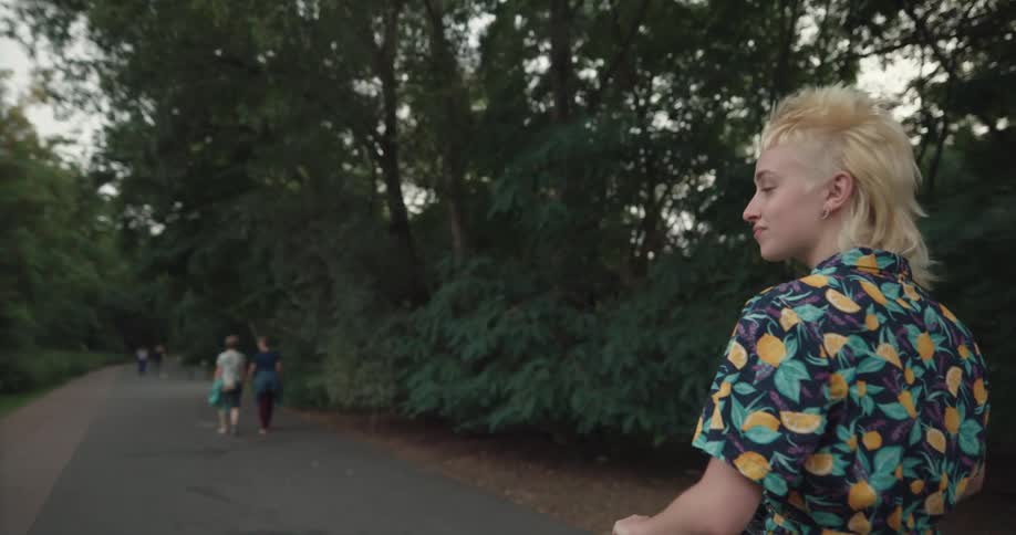 A girl rides a scooter through the park