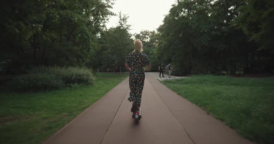 A girl rides her scooter in the park
