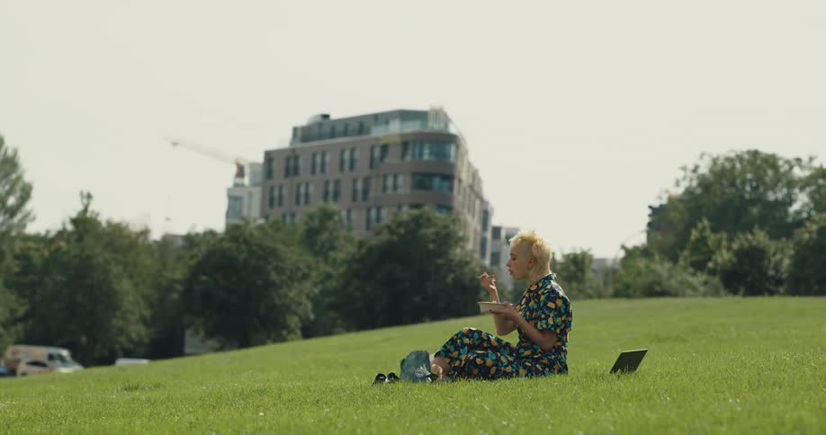 A woman is sitting in a field and eating food